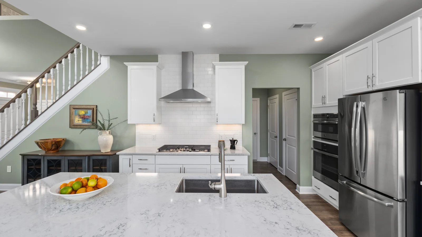 Bright remodeled kitchen with white marble island and open staircase